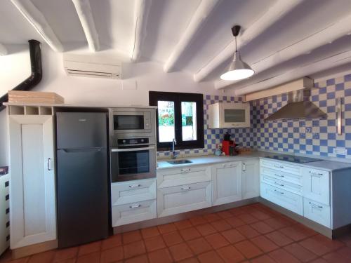 eine Küche mit weißen Schränken und einem schwarzen Kühlschrank in der Unterkunft Sésamo Apartamento in Hervás