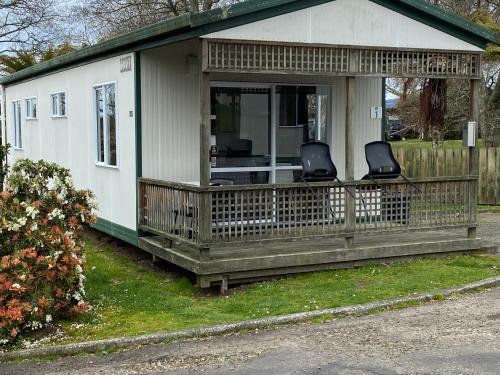 a small house with two chairs on a porch at Rotorua Thermal Holiday Park in Rotorua