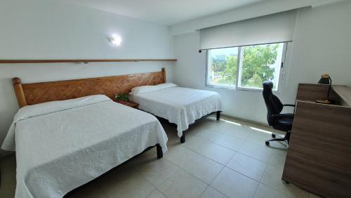 a bedroom with two beds and a desk and a window at Fantastic family villa on the best beach of Cancun in Cancún