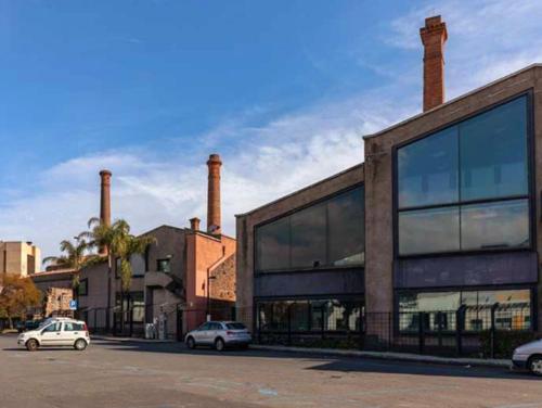 a building with two chimneys and cars parked in front at La Stazione 92 in Catania