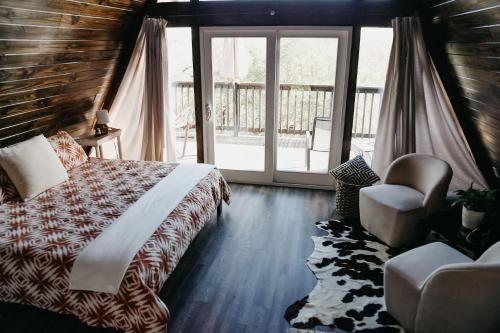 1 dormitorio con 1 cama, 1 silla y 1 ventana en The Maverick: A-Frame w/ Hammock and Tree Top View en New Braunfels