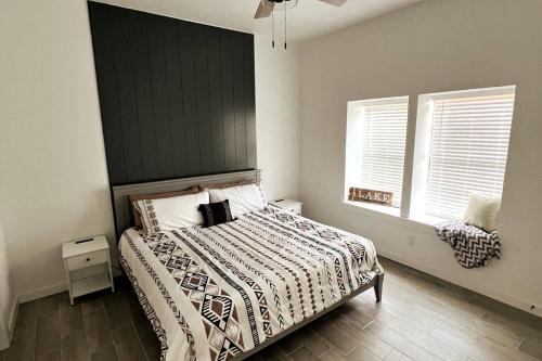 - une chambre avec un lit avec une tête de lit noire et 2 fenêtres dans l'établissement *NEW* Breathtaking Lakeside #1 Home, à Porum