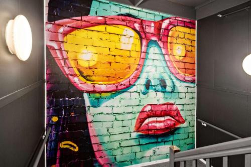 a mural of a face on a brick wall at Aiden by Best Western Harstad Narvik Airport in Harstad