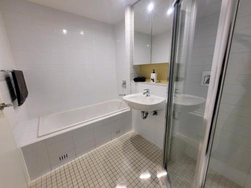 uma casa de banho branca com um lavatório e uma banheira em CityViews @ Glenelg * Pool/Beach * Free Parking * em Glenelg