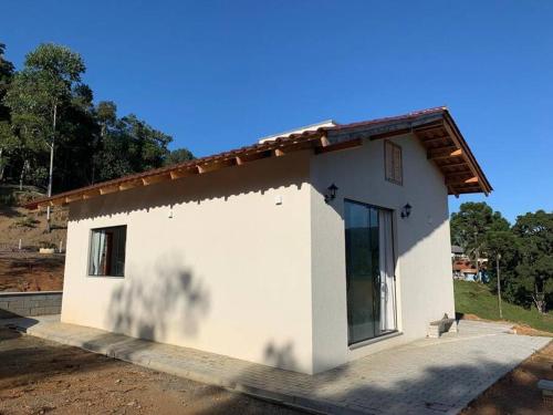 une petite maison blanche avec un chat assis devant elle dans l'établissement Lake House_SC, à Rio Forcação