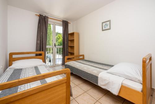 Dos camas en una habitación con ventana. en Apartments Obradović, en Dramalj