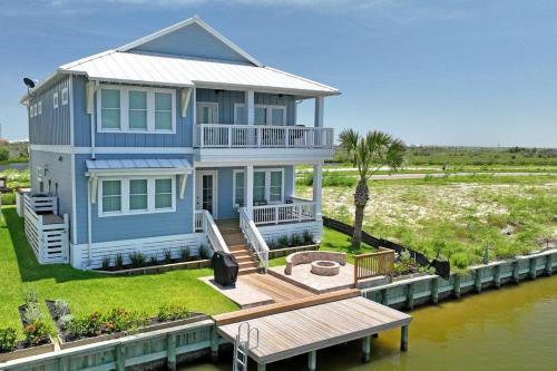 a large blue house on the water with a dock at Nauti Captain in Port Aransas