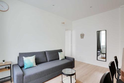- un salon avec un canapé gris et un miroir dans l'établissement Peaceful apartment - 1BR 4P - Levallois-Perret, à Levallois-Perret