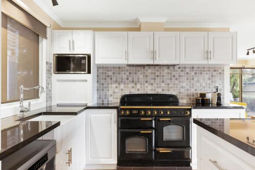 a kitchen with white cabinets and a black stove at Florida Bliss in Smiths Beach