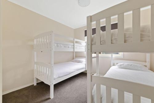 two white bunk beds in a room with a bed at Florida Bliss in Smiths Beach
