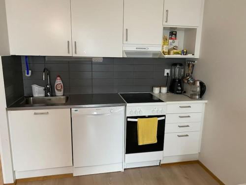 una cocina blanca con armarios blancos y fregadero en Cozy apartment in Rastila, en Helsinki