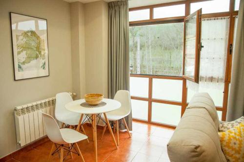 ein Wohnzimmer mit einem Tisch, Stühlen und einem Sofa in der Unterkunft Cumbres de los Picos Apartamento Los Abedules in Poo de Cabrales