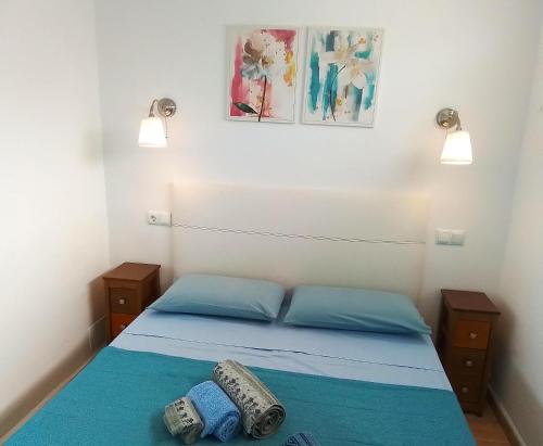 ein Schlafzimmer mit einem Bett mit blauer Bettwäsche und zwei Lichtern in der Unterkunft Oasis Marina Apartament in Costa Del Silencio