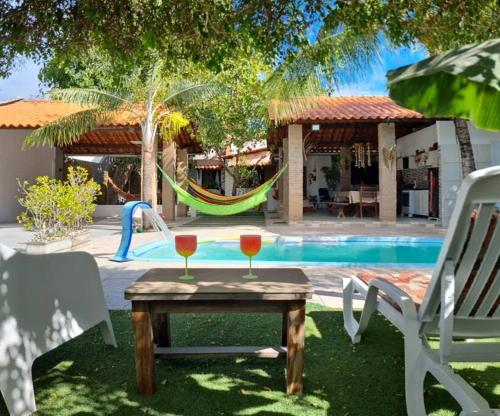 two glasses of wine on a table in front of a pool at Casa linda na Praia do Francês! Caribe Alagoano in Marechal Deodoro