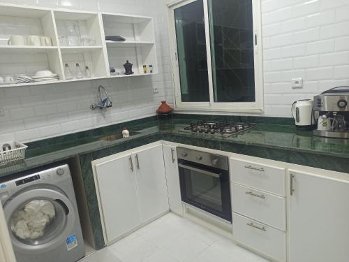 a kitchen with white cabinets and a washing machine at Charmant Appartement Meublé en face de la Mosquée Hassan II : Emplacement Idéal au Cœur de Casablanca in Casablanca