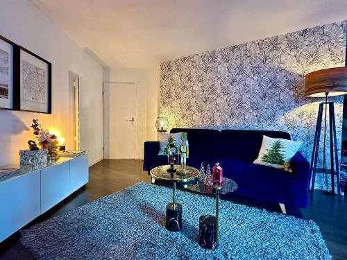 a living room with a blue couch and a table at Appt Vue Place de Toscane - 4min Disneyland-PARIS in Serris