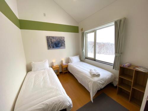 ニセコ町にあるYotei Chaletsのベッド2台と窓が備わる客室です。