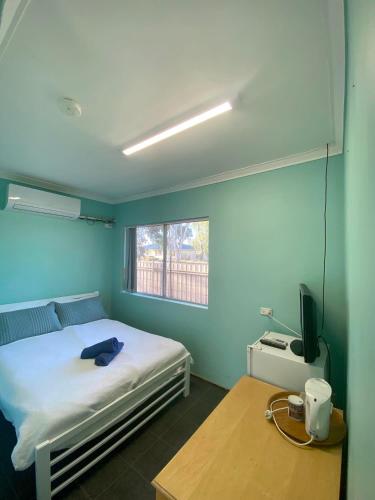 a bedroom with a bed and a table and a window at Bruce Rock Roadhouse and Motel in Bruce Rock