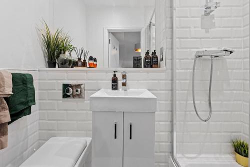uma casa de banho branca com um lavatório e um chuveiro em Small studio in Central ATTENTION Prepayment is needed to the host em Londres