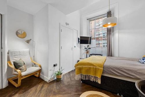 um quarto com uma cama, uma cadeira e uma janela em Small studio in Central ATTENTION Prepayment is needed to the host em Londres