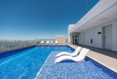 una piscina con 2 sillas blancas en un edificio en 0404 iFreses estudio con Aire Acondicionado y Parqueo, en Curridabat