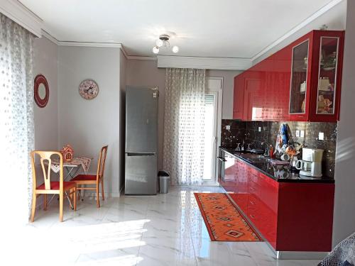 a kitchen with red cabinets and a table with chairs at Maria's sea view condo in Kavala