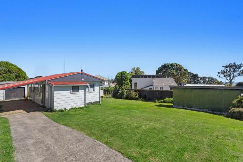 a house with a large yard with a driveway at Back to the Beach Bach in Waiotahi