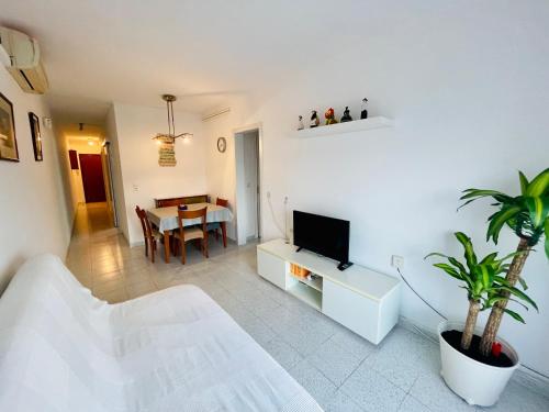 ein weißes Wohnzimmer mit einem TV und einem Tisch in der Unterkunft Barca 1 in Barcelona
