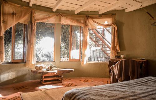 1 dormitorio con cama, mesa y ventanas en Bambuddha - Garden Suite at Lakehouse en San Pedro La Laguna