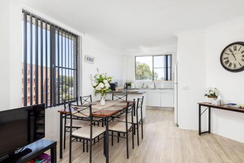 a dining room with a table and chairs and a clock at Views and Pool in a Great Location in Nelson Bay in Nelson Bay