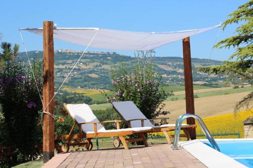 a couple of chairs sitting next to a swimming pool at Country House Binnella in Cingoli