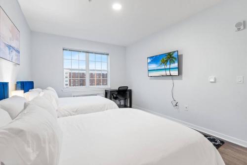 a white bedroom with two beds and a window at Urban Elegance: 20 Minutes to NYC (Gym, Laundry) in Jersey City
