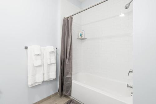 a white bathroom with a shower and a tub at Urban Elegance: 20 Minutes to NYC (Gym, Laundry) in Jersey City