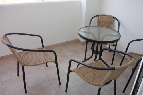 three chairs and a glass table and a table and chairs at Mandorla Apartments in Lardos