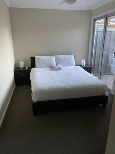 a bedroom with a bed with white sheets and a window at Tasha's Apartments - Andrews Farm in Smithfield