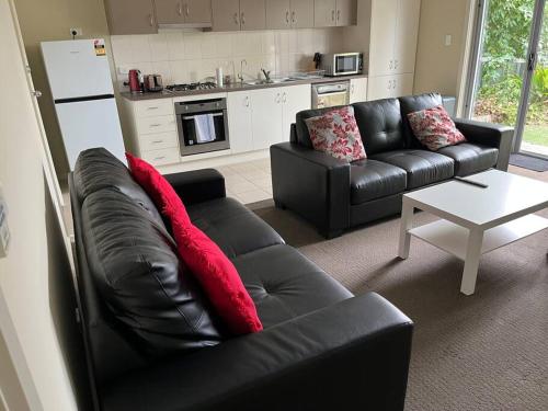 a living room with a black leather couch and a table at Tasha's Apartments - Andrews Farm in Smithfield