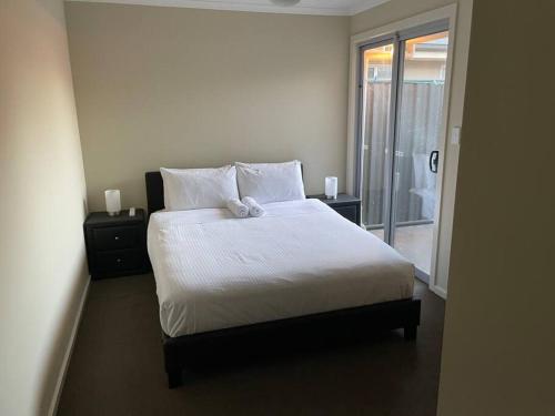 a bedroom with a bed with white sheets and a window at Tasha's Apartments - Andrews Farm in Smithfield