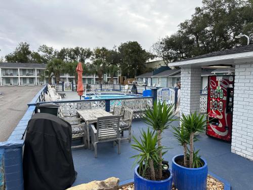 un patio con mesa, sillas y piscina en Gulf Coast Inn, en Gulf Breeze