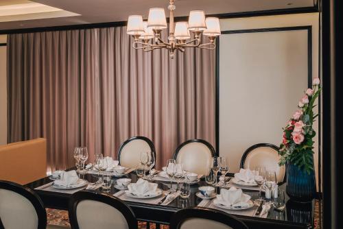 a dining room with a table and chairs and a chandelier at La Vela Hue Hotel in Hue