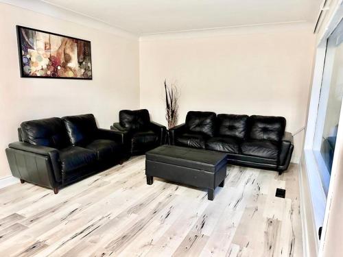 a living room with black leather couches and a table at Main floor Room with Queen Bed, Free Parking and Free wi-fi and shared washroom near Fairview Park Mall (Room 2) in Kitchener