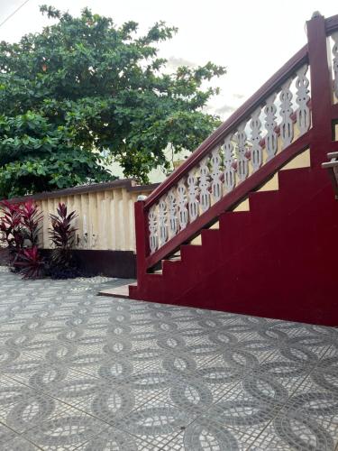 a red stair railing on a sidewalk next to a fence at Elitineide Guest House in São Tomé