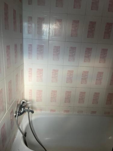 a bath tub in a bathroom with pink tiles at Elitineide Guest House in São Tomé