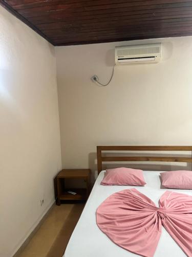 1 Schlafzimmer mit 2 Betten mit rosa Bettwäsche und einem Ventilator in der Unterkunft Elitineide Guest House in São Tomé