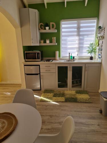 a kitchen with green walls and a table and a microwave at Green Door Oasis in Christ Church