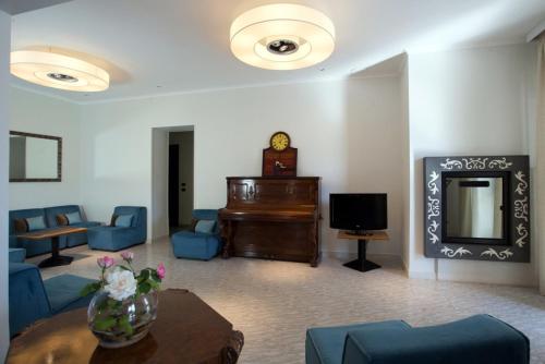 a living room with a piano and blue furniture at Hotel Il Gabbiano in Sabaudia