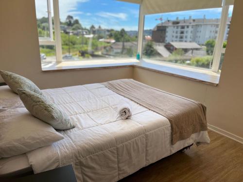 a bed in a bedroom with a large window at Departamento Cercano al Lago Llanquihue in Puerto Varas