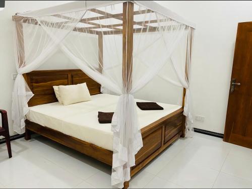 a bedroom with a canopy bed with white sheets at Rebeka’s Place in Dickwella