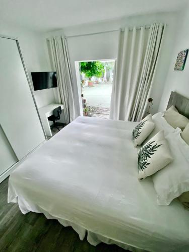 a large white bed in a bedroom with a window at Casa Irauna in Sao Paulo