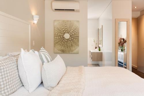 a bedroom with a white bed with white pillows at The Urban Beach House in Dunsborough