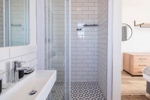 biała łazienka z prysznicem i umywalką w obiekcie Apartment with stunning views of Table Mountain w Kapsztadzie